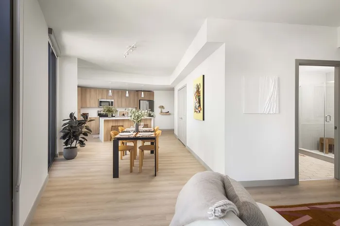 Bright, open-concept living and dining area with modern kitchen, sleek hardwood floors, and elegant decor.