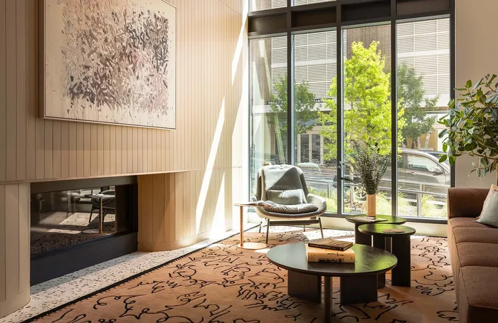 Elegant and cozy living room with floor-to-ceiling windows, chic artwork, plush seating, and abundant natural light.