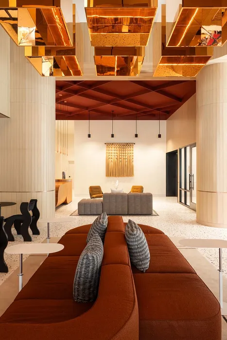 Sophisticated apartment lobby with modern decor, featuring plush seating, artistic ceiling lights, and elegant wall art.