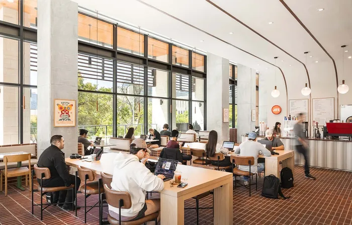 Bright and modern cafe with large windows, vibrant decor, and people working on laptops in an inviting atmosphere.