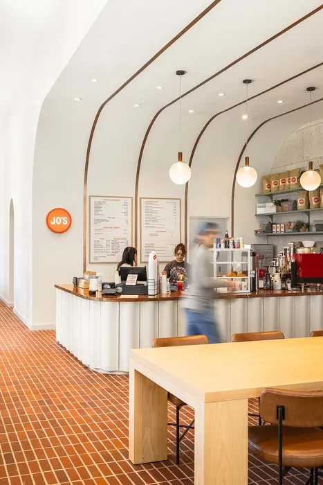 Stylish cafe interior with modern design, featuring a brick-patterned floor, wooden counters, and hanging globe lights.