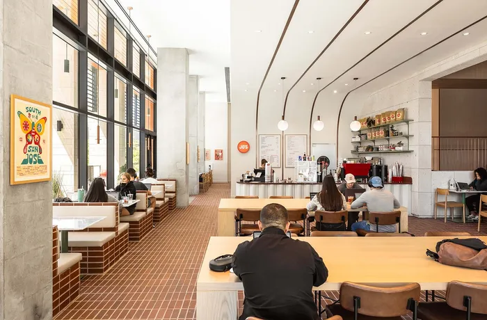 Bright and inviting coffee shop with modern decor, spacious seating, and large windows perfect for natural light.