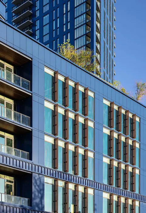 Modern high-rise building with sleek blue facade and large glass windows, boasting stylish urban living with expansive city views.
