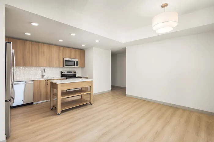 Modern open kitchen with sleek wooden cabinetry, stainless steel appliances, and ambient lighting, offering a spacious and inviting atmosphere.