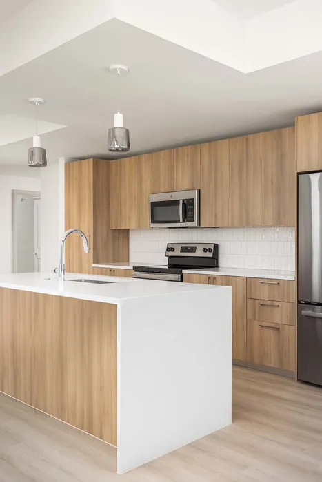 Modern kitchen with sleek wooden cabinets, polished white countertops, and stainless steel appliances, offering a bright and airy cooking space.