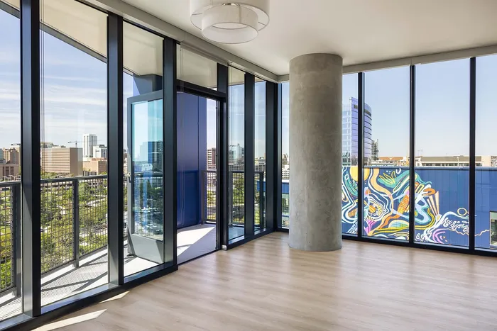 Sleek urban apartment with floor-to-ceiling windows offering panoramic city views and vibrant mural accents.