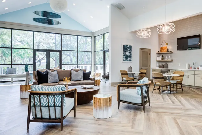 Bright, airy living space with floor-to-ceiling windows, stylish wooden furniture, and modern decor, featuring an inviting lounge area perfect for relaxation and entertainment.