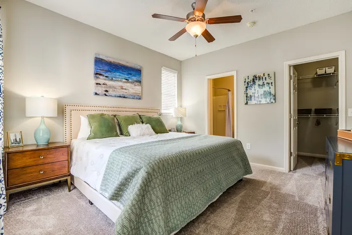 Inviting bedroom with plush carpet, elegant bed, vibrant artwork, and ample closet space.