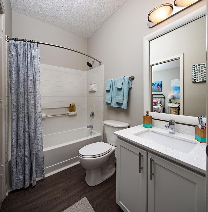 Modern bathroom with elegant fixtures, a pristine bathtub with shower, and a sleek sink with ample counter space, offering a serene and stylish atmosphere.