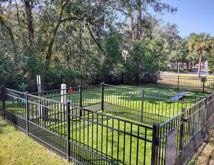 Charming dog park with lush green grass and secure fencing, nestled among tranquil trees, perfect for pet playtime.