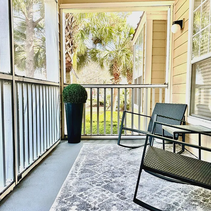 Charming screened porch with cozy seating and lush garden views, perfect for relaxation.