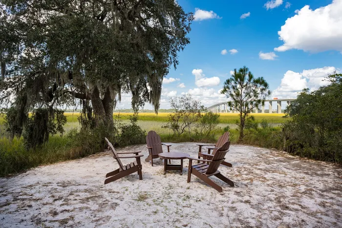 Tranquil outdoor seating area amidst lush greenery with charming views of the bridge under a vibrant blue sky.