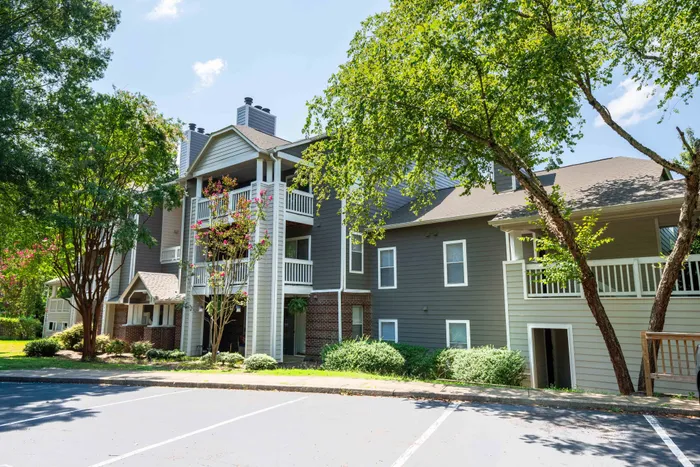 Charming apartment complex with modern design and spacious balconies, nestled among lush greenery and vibrant trees.