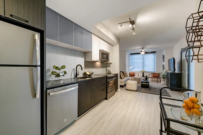Modern open-concept kitchen and living area with sleek appliances, stylish decor, and natural lighting enhancing a cozy ambiance.