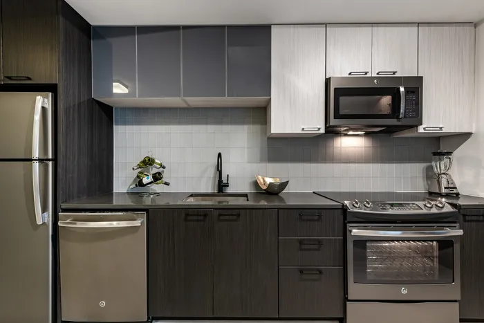 Modern kitchen with sleek dark wood cabinetry, stainless steel appliances, and elegant black faucet, perfect for culinary enthusiasts.