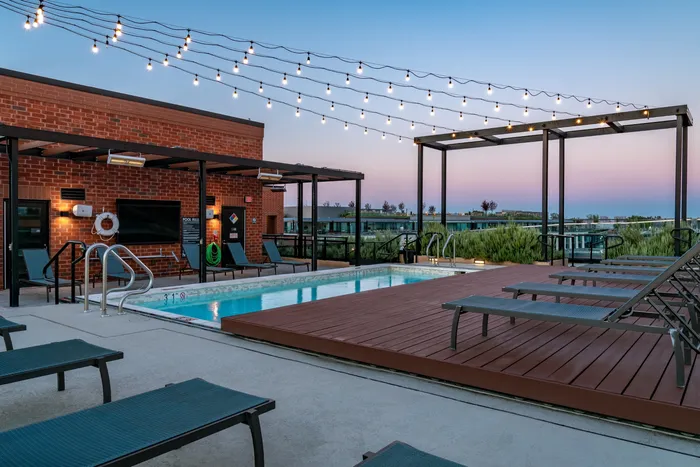 Chic rooftop pool with cozy lounge area, ambient string lights, and stunning sunset views.