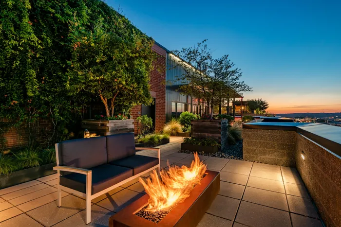 Luxurious rooftop terrace featuring elegant seating and a modern fire pit, set against a stunning sunset backdrop.