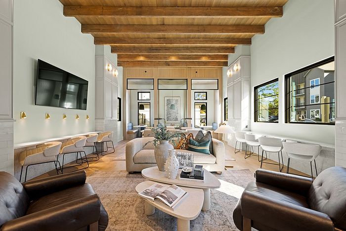 Luxurious living room with high wood-beamed ceilings, stylish seating area, and large windows providing ample natural light.