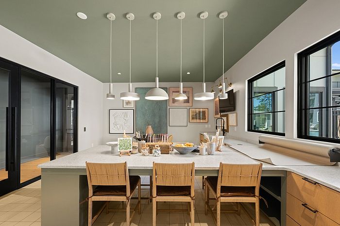 Modern kitchen with sleek pendant lighting, chic wooden chairs, large windows, and stylish decor.