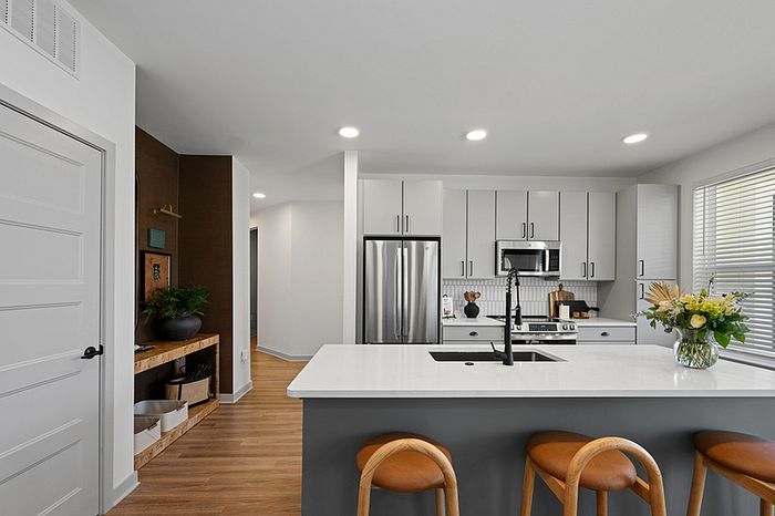 Modern kitchen with sleek white cabinets, stainless steel appliances, and a stylish island with wooden bar stools, offering a bright, welcoming space.