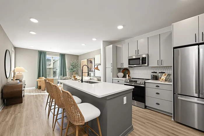 Modern open-concept kitchen and living area featuring sleek cabinetry, stainless steel appliances, and a stylish island with seating.