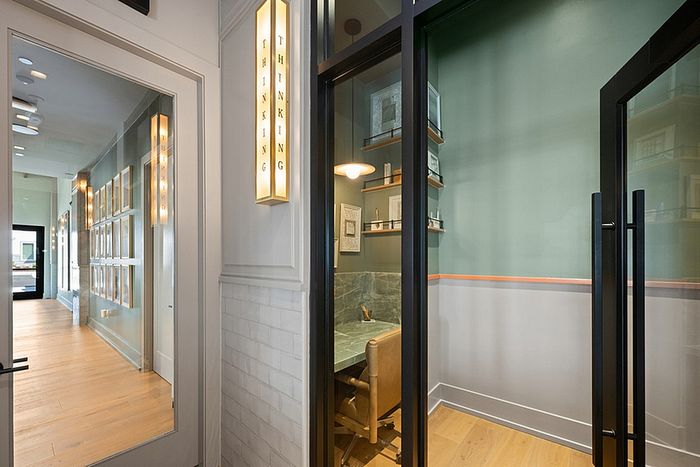 Sleek modern hallway with stylish wall art and a cozy private office space featuring elegant shelving and a comfortable chair.
