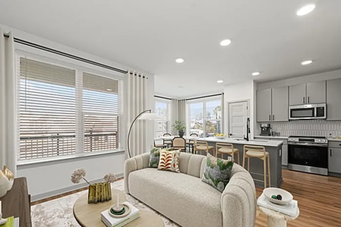 Modern apartment with an open-plan living area featuring a cozy sofa, elegant kitchen with bar stools, and large windows illuminating the space.