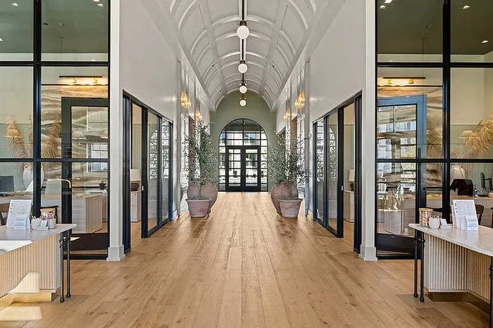 Elegant hallway with high arched ceiling, wooden floors, and glass office partitions creating a modern, airy workspace.