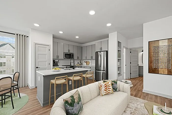 Modern open-concept living space with a chic kitchen, cozy sofa, and elegant dining area, highlighted by natural light.