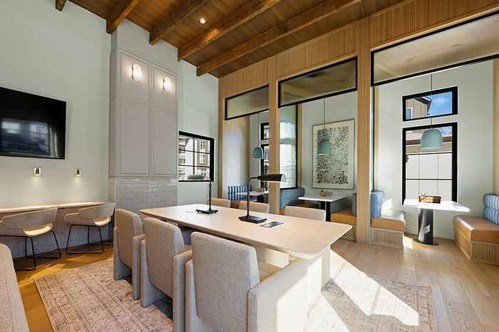 Chic modern communal space with open seating, stylish pendant lighting, and warm wooden accents.