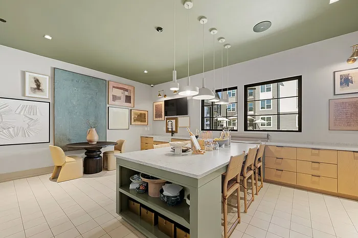 Elegant kitchen with modern design features a central island, stylish pendant lighting, and an artistic gallery wall.
