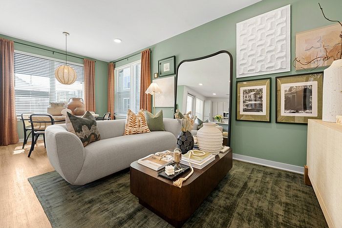 Contemporary living room with chic gray sofa, accent pillows, elegant wooden coffee table, and stylish wall art in a soothing green space.