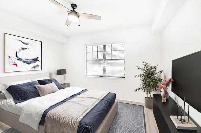 Chic and cozy bedroom with modern decor, featuring a plush bed with navy accents, abstract wall art, sleek black furniture, vibrant plant, and elegant lighting.