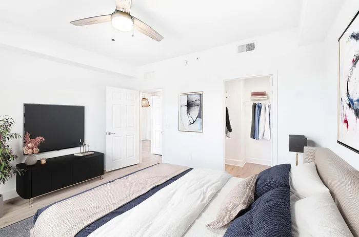 Bright and airy bedroom showcasing modern decor, plush bedding, and a sleek entertainment center.