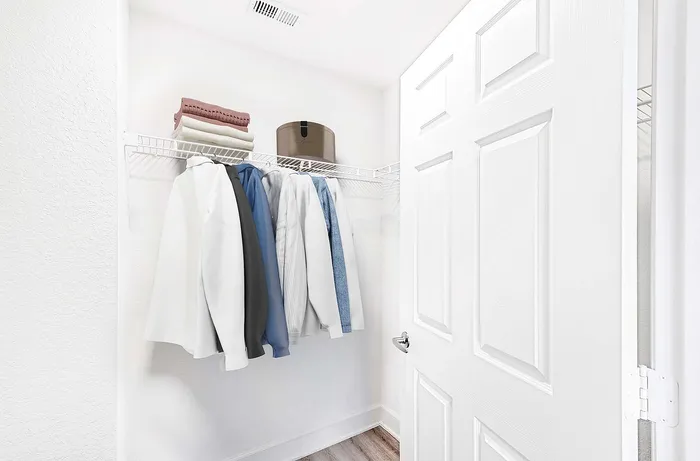 Bright and spacious walk-in closet with organized shelving and a variety of neatly hung clothes.