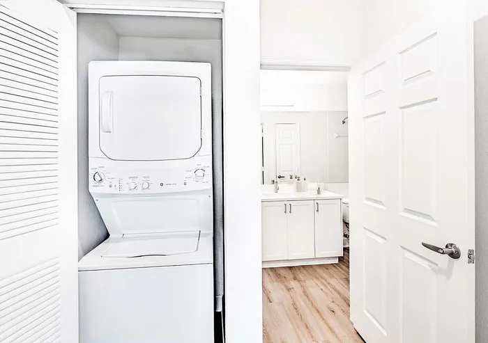 Bright and modern apartment featuring an in-unit washer and dryer beside a stylish bathroom with elegant cabinetry and sleek fixtures.