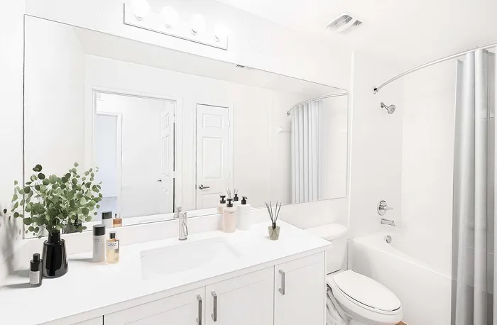 Bright, modern bathroom featuring a sleek vanity with chic accessories, a large mirror, and a relaxing bathtub.
