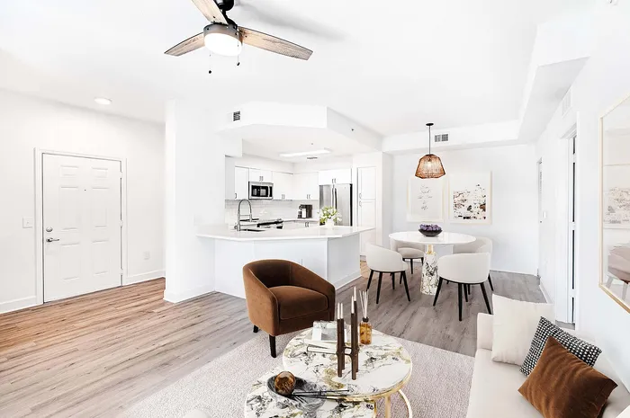 Modern open-plan living space featuring a sleek kitchen with stainless steel appliances, cozy dining area, and elegant marble coffee table.