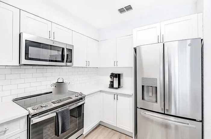 Modern kitchen with sleek stainless steel appliances, pristine white cabinetry, and a stylish subway tile backsplash.