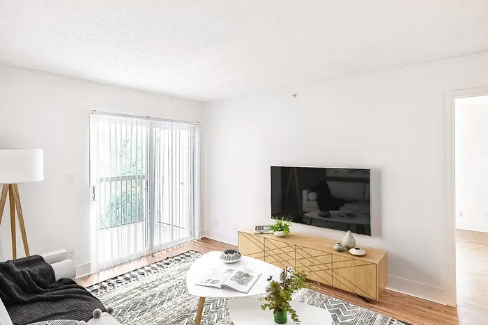 Bright, modern living room with a stylish TV setup, cozy seating, and large windows offering natural light.