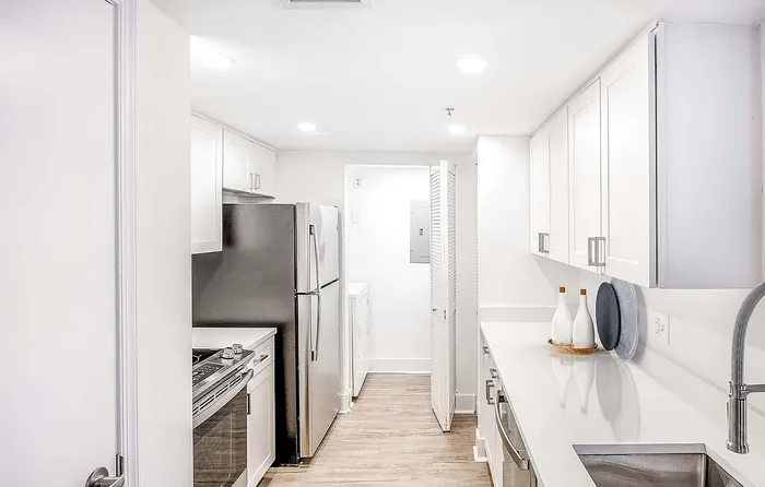 Sleek modern kitchen with stainless steel appliances, elegant white cabinetry, and glossy countertops.