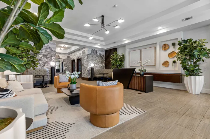 Luxurious apartment lobby featuring modern decor, plush seating, stylish wall art, and lush greenery creating an inviting and elegant atmosphere.