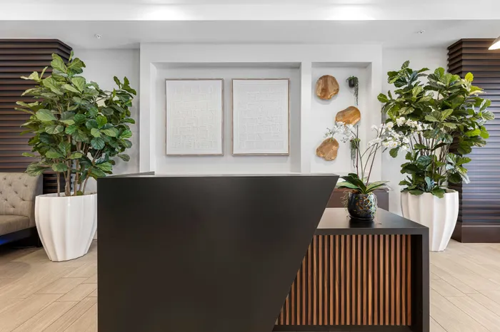 Elegant lobby with modern decor featuring lush greenery, contemporary art, and sleek reception desk, creating a welcoming and sophisticated atmosphere.