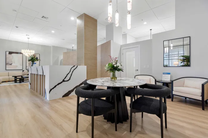 Elegant open-concept living space featuring a stylish dining area with a chic marble table, modern lighting, and sophisticated decor.
