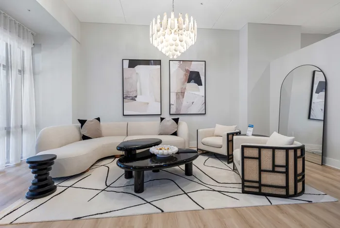 Elegant living room with modern curved sofa, chic black coffee tables, and stylish wall art under a designer chandelier.