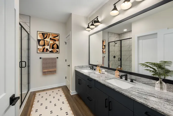 Luxurious bathroom showcasing modern double sinks with granite countertops, elegant black fixtures, artistic wall decor, and a sleek glass shower enclosure.
