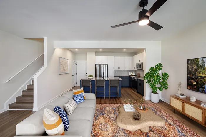 Contemporary open-concept living room and kitchen with stylish decor, featuring cozy seating, a vibrant rug, and modern appliances, perfect for comfortable living.
