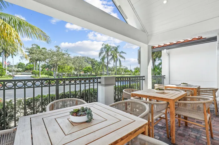 Charming terrace with elegant wooden tables and chairs overlooking lush palm trees and vibrant greenery, perfect for outdoor dining and relaxation.