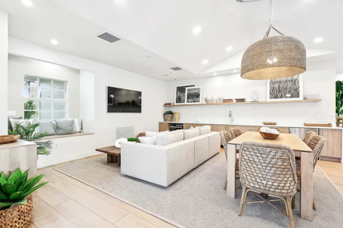 Inviting open-plan living and dining area with modern decor, featuring a cozy window seat, stylish woven furniture, and soft natural lighting.