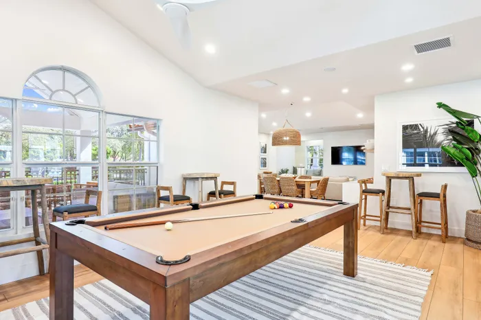 Inviting modern lounge featuring a pool table, stylish seating, and bright natural lighting, ideal for social gatherings.